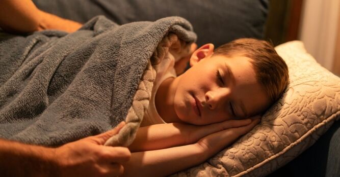 Roditelj pokriva dijete koje mirno spava – siguran san i prevencija noćnih mora kod djece