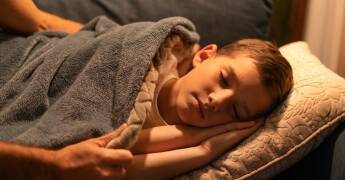 Roditelj pokriva dijete koje mirno spava – siguran san i prevencija noćnih mora kod djece