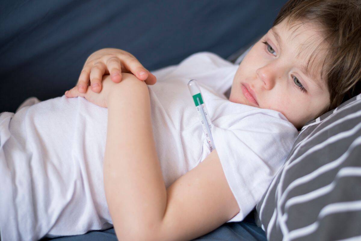 Djete leži na kuču i mjeri temperaturu