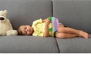 Dijete leži na kauču i drži igračku, tiho i zamišljeno